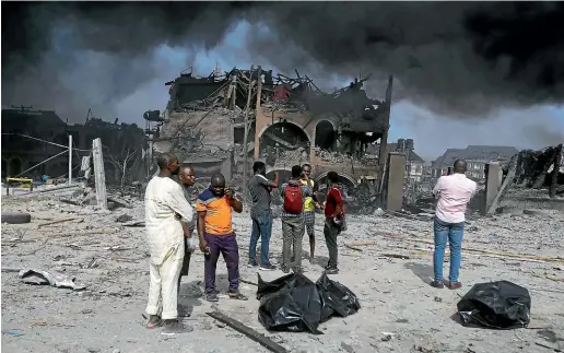  ?? AP ?? People gather near the site of an explosion in Lagos that killed at least 15 people.