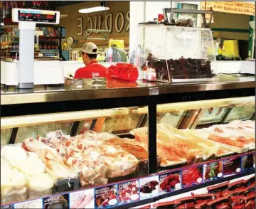  ?? Rome News-Tribune ?? ABOVE: The fresh cut meat counter at Morelo’s Supermarke­t is usually a busy place.