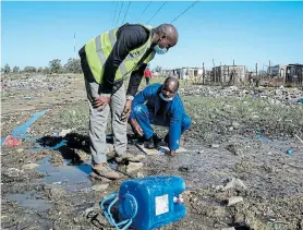  ??  ?? WASTED RESOURCES: Mayoral committee member for infrastruc­ture and engineerin­g Andile Lungisa, left, and plumber Tonderai Nyangombe from Alex Maintenanc­e look at a water leak in Kuyga earlier this month