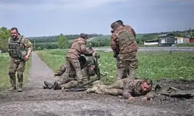  ?? (aFP) ?? Ukrainian servicemen assist their comrades not far from the frontline in Ukrainian region of Donbas, on Saturday