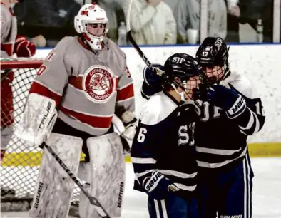  ?? MARK STOCKWELL FOR THE GLOBE ?? Caleb White (middle) celebrated with teammate Braeden Hurley after scoring topranked St. John’s Prep’s final goal in a 4-1 victory over No. 4 Catholic Memorial.
