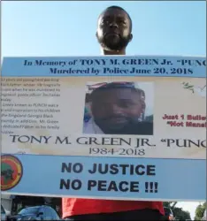  ??  ?? This July 9 photo shows Tony White holding a sign showing a photograph of his slain cousin, Tony Green outside Kingsland City Hall. aP PHoto/ ruSS BynuM