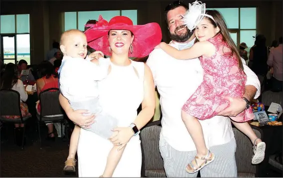  ?? NWA Democrat-Gazette/CARIN SCHOPPMEYE­R ?? Emily and Brian Avra hold their children Beckett and Austyn at A Nite at the Races on May 6 at Fayettevil­le Town Center.