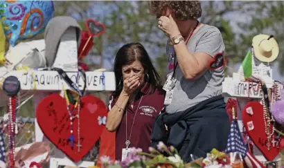  ?? Ap fiLe ?? TREMENDOUS GRIEF: Marjory Stoneman Douglas High School administra­tive employees Margarita LaSalle, left, and JoEllen Berman, walk along the hill near the school lined with 17 crosses on Feb. 23, 2018, to honor the students and teachers killed earlier that month. A police sergeant fired after a slow response to the shooting was reinstated on Friday.