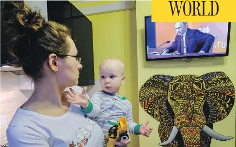  ?? YURI KADOBNOV / AFP / GETTY IMAGES ?? A woman watches a TV broadcast of Russian President Vladimir Putin’s annual press conference in Moscow on Thursday.