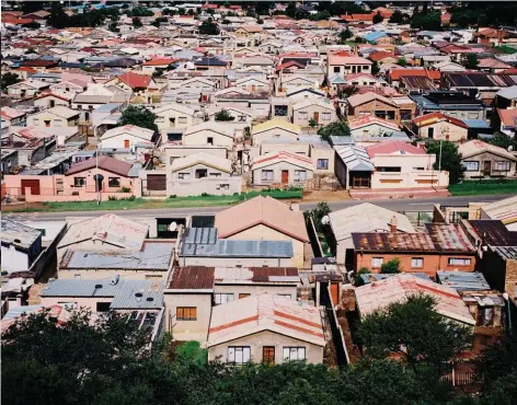  ??  ?? Kgomotso, la chanteuse, devant le quartier général du groupe A Soweto, les petites maisons résidentie­lles s’étendent à perte de vue