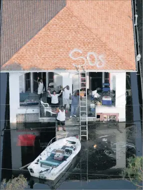  ?? PICTURES: AP / REUTERS ?? STRANDED: New Orleans residents wait to be rescued from the floodwater­s of Hurricane Katrina in New Orleans on August 31, 2005.