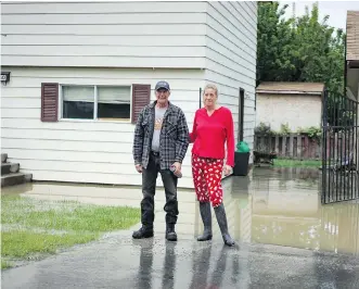  ?? NICK EAGLAND ?? Elsa Edwards and Chris Roger bought their home one month ago and say that thanks to immense efforts by their neighbours, they’ve been spared from flood damage so far.