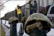  ?? ANDREW HARNIK — THE ASSOCIATED PRESS ?? National Guard helmets are placed on top of barricades as workers install razor wire to the top of fencing on Capitol Hill in Washington on Thursday.