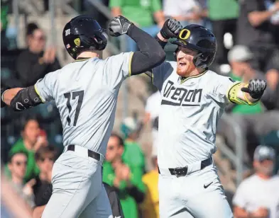  ?? BEN LONERGAN/THE REGISTER-GUARD ?? Oregon outfielder Justin Cassella and Oregon infielder Drew Smith celebrate a home run by Cassella on Saturday.