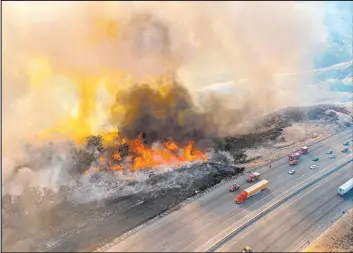  ?? The Associated Press ?? An aerial photo released by Los Angeles County Fire Department Air Operations shows traffic passing a wildfire Saturday off Interstate 5 near of Castaic, Calif.