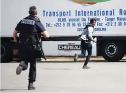  ??  ?? CALAIS: A policemen chases a youth - suspected of being a migrant in a lorry park on the outskirts of Calais yesterday, near the site of the former area known as ‘The Jungle’. Authoritie­s are on alert after the arrival of several hundred migrants in...