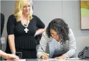  ??  ?? Karen Rodriguez, 18, signs documents, witnessed by Kelly Jo Cannon, left, relating to the federal lawsuit.