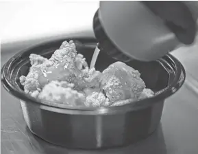  ?? ?? A chef squeezes sauce onto a new “Saucy Nuggets” KFC menu item during a media event at the KFC headquarte­rs test kitchen at the Yum! Brands headquarte­rs in Louisville March 27.