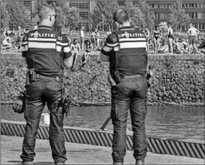  ??  ?? Agenten houden toezicht terwijl mensen naar verkoeling zoeken in het Amsterdams­e IJ.
(Foto: De Telegraaf)