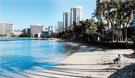  ?? CALEB JONES/AP ?? A man sits on a nearly empty Waikiki Beach last week in Honolulu. Hawaii officials plan to reboot the tourism-based economy later this month.