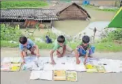  ?? PTI ?? School students lay books out on the roads to dry them in a floodaffec­ted village in Morigaon district of Assam on Wednesday.