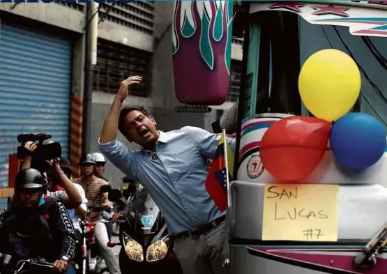  ??  ?? Carlos Ocariz, candidato da oposição ao governo do Estado de Miranda, acena a simpatizan­tes a caminho de sua seção eleitoral, em Caracas, no domingo (15)