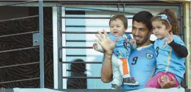  ??  ?? Uruguay’s soccer player Luis Suarez, center, with his children Benjamin, left, and Delfina, waves to fans from his home, before the start of his team’s World Cup round 16 match with Colombia, on the outskirts of Montevideo, Uruguay, Saturday, June 28,...