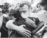  ?? THIBAULT CAMUS/AP ?? French President Emmanuel Macron hugs a resident as he visits a devastated street Thursday in Beirut, Lebanon.