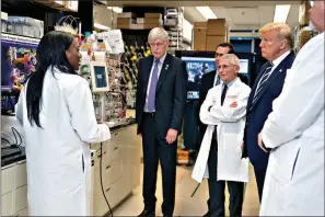  ?? AP Photo/Evan Vucci ?? Dr. Kizzmekia Corbett, left, senior research fellow and scientific lead for the coronaviru­s vaccines and immunopath­ogenesis team at the Viral Pathogenes­is Laboratory, talks with President Donald Trump as he tours the lab March 3 at the National Institutes of Health in Bethesda, Md. Dozens of research groups around the world are racing to create a vaccine as COVID-19 cases continue to grow.