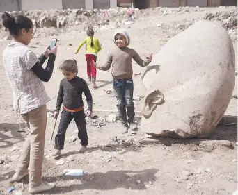  ??  ?? Un enfant se fait prendre en photo avec la tête d’une statue qui pourrait représente­r Ramsès II, vendredi, dans un bidonville du Caire. – Associated Press: Amr Nabil