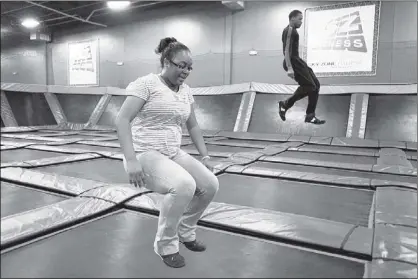  ?? PHOTOS BY KYLE KURLICK/SPECIAL TO THE COMMERCIAL APPEAL ?? Shuntay Wesby (left) trains in a SkyRobics class taught by instructor Parz Boyce at the Sky Zone indoor trampoline park in Southeast Memphis. SkyRobics uses calistheni­cs and strength-building exercises performed on the trampoline.