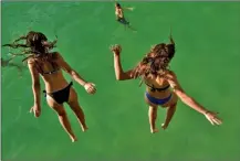  ?? The Associated Press ?? Two women jump from a platform over the water at La Concha beach in San Sebastian, Spain, Friday.