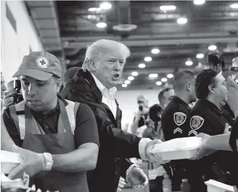  ?? THE ASSOCIATED PRESS ?? President Donald Trump passes out food and meets people affected by Hurricane Harvey Saturday during a visit to the NRG Center in Houston.