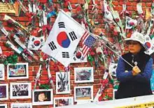  ?? AFP ?? A supporter of impeached ex-president Park Geun-hye stands in front of a wall displayed with pictures of Park outside the former leader’s residence in Seoul yesterday.