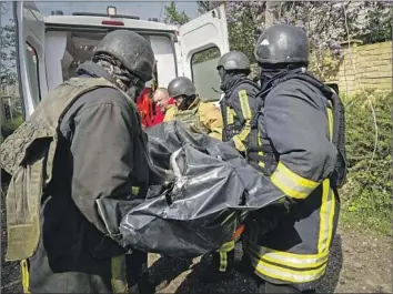  ?? Andrii Marienko Associated Press ?? EMERGENCY workers transport the body of a resident who was killed in the Kharkiv region in northeaste­rn Ukraine. Russia has intensifie­d its air assaults, deploying hypersonic missiles in a recent major attack on Kyiv.
