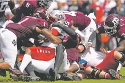  ?? SAM CRAFT/ASSOCIATED PRESS ?? UNM running back Aaron Dumas is tackled for a loss by Texas A&M defenders Saturday in College Station, Texas. The Lobos were rolled 34-0.