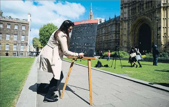  ?? JUSTIN TALLIS / AFP ?? Una empleada de una casa de apuestas escribe las primeras conjeturas sobre los resultados del 8 de junio, junto al Parlamento de Londres