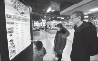  ?? LONG WEI / FOR CHINA DAILY ?? Customers check prices of food products on a touch screen at a supermarke­t in Hangzhou, Zhejiang province.