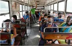  ?? —AFP ?? Playing safe: Passengers wearing face shields and masks as they ride a bus in Manila.