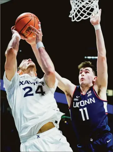  ?? Jeff Dean / Associated Press ?? Xavier forward Jack Nunge shoots as UConn’s Alex Karaban defends during the first half on Saturday in Cincinnati.