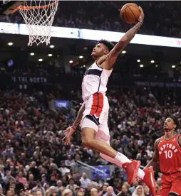  ?? (Reuters) ?? WASHINGTON WIZARDS forward Kelly Oubre Jr. rises to the hoop for a dunk during the Wizards’ 107-96 road victory over the Toronto Raptors on Sunday night. Oubre Jr. finished with 10 points off the bench as Washington never trailed in the contest in...