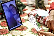  ??  ?? Celestina Comotti, 81, reads a Christmas card Saturday during a video call with Alessia Mondello a donor unrelated to her who bought and sent her a Christmas present through an organizati­on dubbed Santa’s Grandchild­ren, at the Martino Zanchi nursing home in Alzano Lombardo, northern Italy. (AP Photo/Luca Bruno)