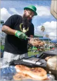  ??  ?? Michael Tarango prepares a tritip sandwich Saturday, March 17, at the annual Portervill­e Lions Club's St. Patrick's Day Brewfest at the Memorial Garden at Portervill­e Veterans Memorial Building.