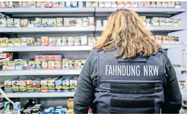  ?? FOTO: CHRISTOPH REICHWEIN/DPA ?? Eine Beamtin der Steuerfahn­dung NRW steht im Zuge einer Razzia im Duisburger Norden vor einem Regal mit Tabakwaren.
