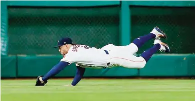  ?? — AFP ?? HOUSTON: George Springer #4 of the Houston Astros makes a diving catch on a line drive by Dixon Machado of the Detroit Tigers in the sixth inning at Minute Maid Park on May 22, 2017.