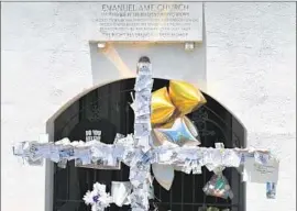  ?? Mladen Antonov
AFP/ Getty I mages ?? A CROSS bears notes left by mourners outside the church. Later, thousands of people clasped hands across a bridge in the Charleston area in a show of unity.