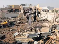  ?? REUTERS ?? People stand on a roof of a house amidst debris of a passenger plane, crashed in a residentia­l area near an airport in Karachi, Pakistan, May 22.