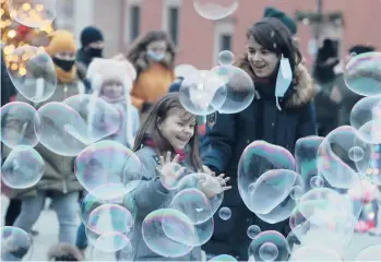  ?? CZAREK SOKOLOWSKI/AP ?? Playtime amid the pandemic: People try to maintain social distance to prevent the spread of COVID-19 Saturday as they play with soap bubbles in Castle Square in Warsaw, Poland. The country has logged more than 1.3 million confirmed coronaviru­s infections and more than 29,000 deaths from COVID-19, according to Johns Hopkins University data.