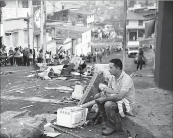  ?? John Moore Getty Images ?? A FATHER rests before sunrise with his daughter while someone holds their place in a long line to buy food in San Cristobal. Protests over the economy have plagued President Nicolas Maduro, who faces a recall vote.