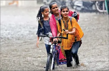  ?? REUTERS ?? Girls push a bicycle through a waterlogge­d road during heavy rain in Ahmedabad on Thursday.