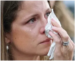  ?? ?? Tearful: A well-wisher dabs her eyes after leaving a bunch of flowers