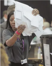  ?? AP PHOTO ?? FINANCIAL FALLOUT: A member of the election staff, above, prepares to count ballots in Maidenhead, England, yesterday as a stock trader in Tokyo, below, reacts to British election results.