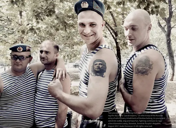  ?? ?? Two young soldiers showing their muscles and their tattoos during the day of the "paratroope­rs," an elite troop of the Russian army of which many inhabitant­s of Donbas belong. As young and old drink vodka, sing and have fun, fighting continues to rage a few kilometers away, Donetsk, Donetsk People's Republic, August 2017. Aude Osnowycz © All rights reserved.
