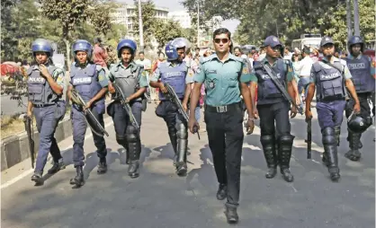  ??  ?? DHAKA: Bangladesh­i policemen guard, as activists who have been campaignin­g for capital punishment for war criminals march in a rally, behind, to protest against a nationwide strike called by the main Islamist party, Jamaat-e-Islami in Dhaka yesterday....